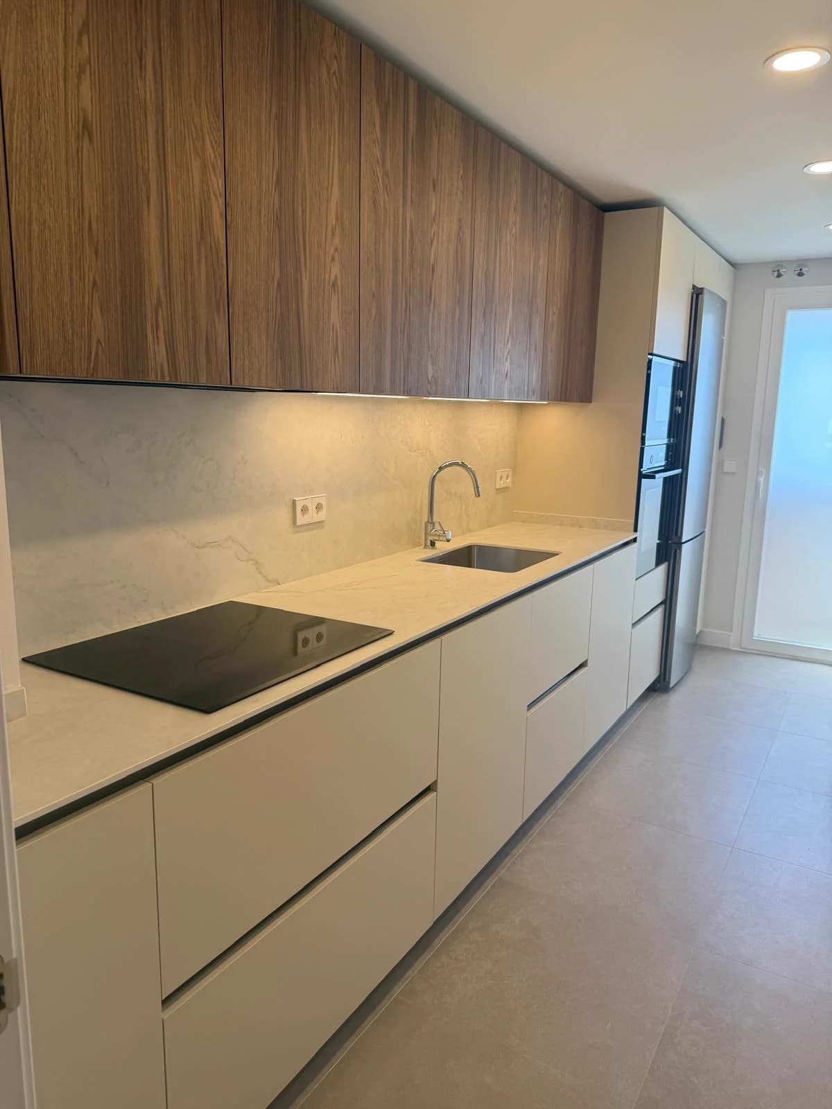 Roble y crema — vista principal de la cocina, obra real en Madrid